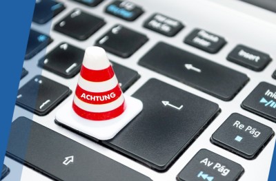 Auf einer Tastatur steht eine kleine Pylone mit der Aufschrift "Achtung" Achtung