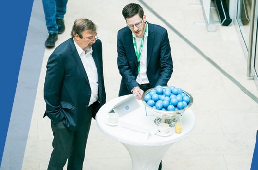 Zwei Herren besprechen sich an einem Stehtisch