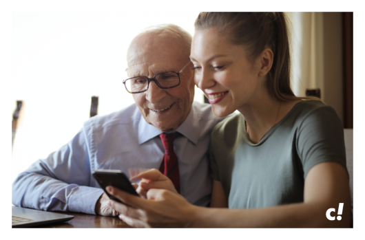 Enkelin zeigt ihrem Großvater etwas auf dem Smartphone.