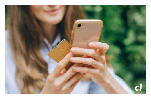 Frau hat eine Kreditkarte in der Hand und schaut auf ein Smartphone.
