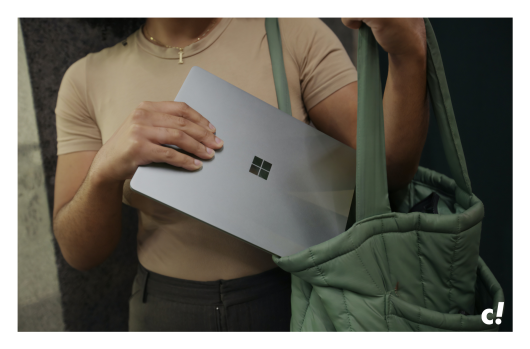 Eine Frau die einen Laptop von Microsoft in ihre Tasche packt