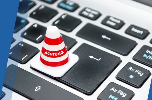 Auf einer Tastatur steht eine kleine Pylone mit der Aufschrift "Achtung"