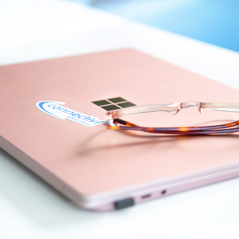 Eine Brille liegt auf einem blassrosa Notebook