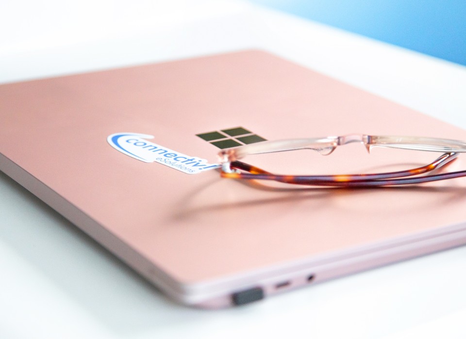Eine Brille liegt auf einem blassrosa Notebook