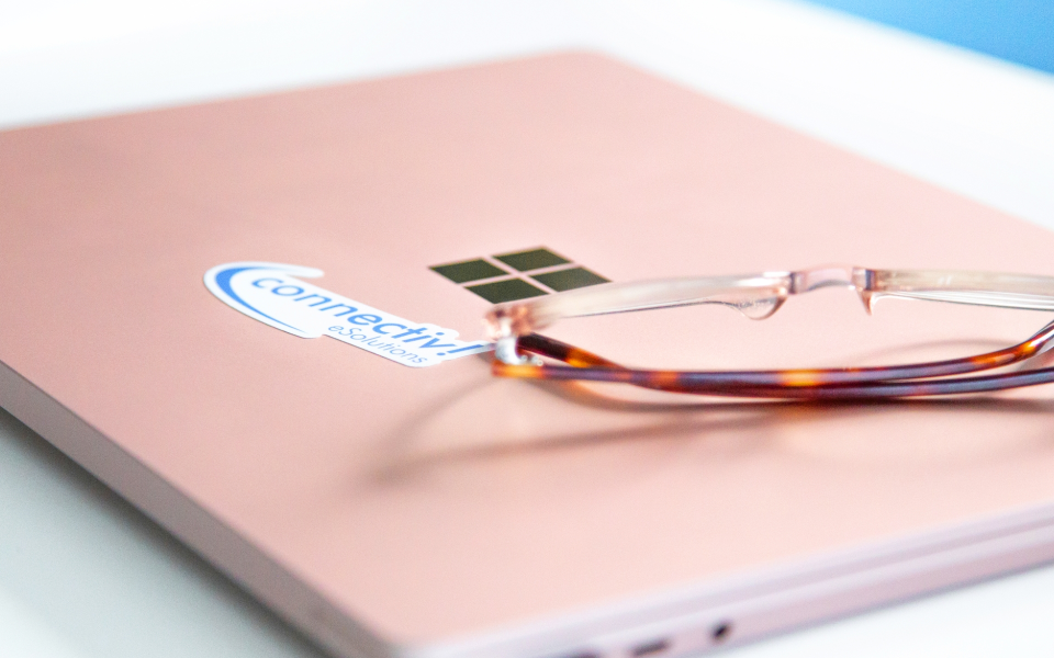 Eine Brille liegt auf einem blassrosa Notebook