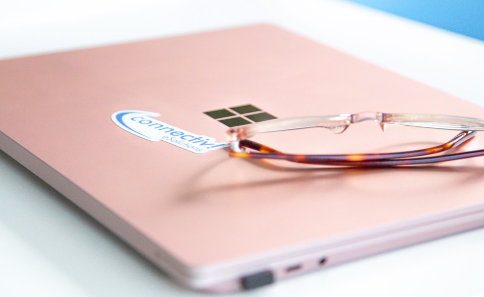 Eine Brille liegt auf einem blassrosa Notebook