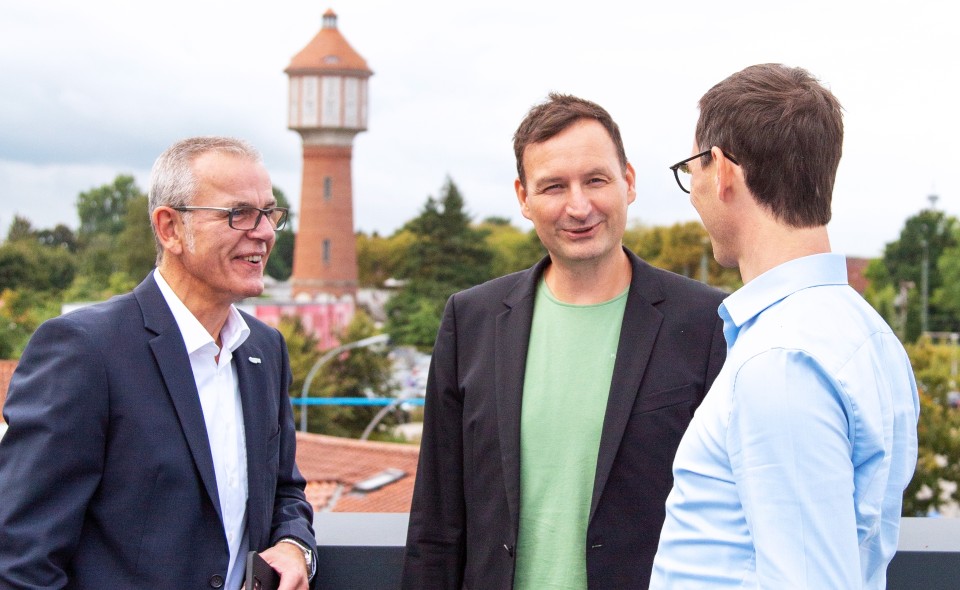 Drei Personen unterhalten sich auf der Dachterrasse